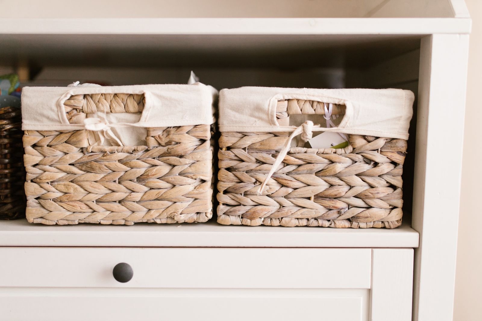 Woven storage baskets with linen liners organized on a white shelf for simple DIY storage