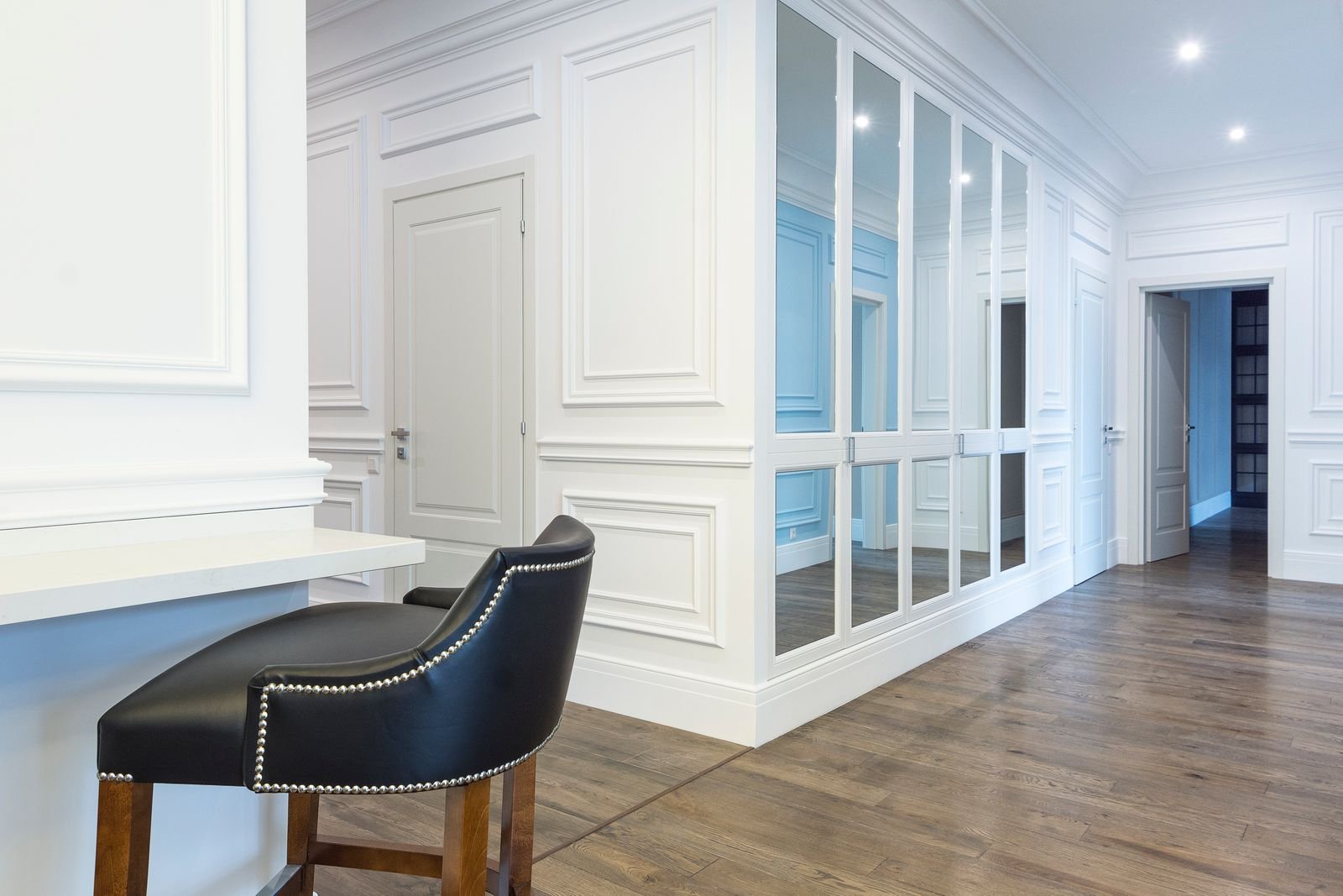 Bright small room with full-height mirrored closet doors reflecting light across the wood floor