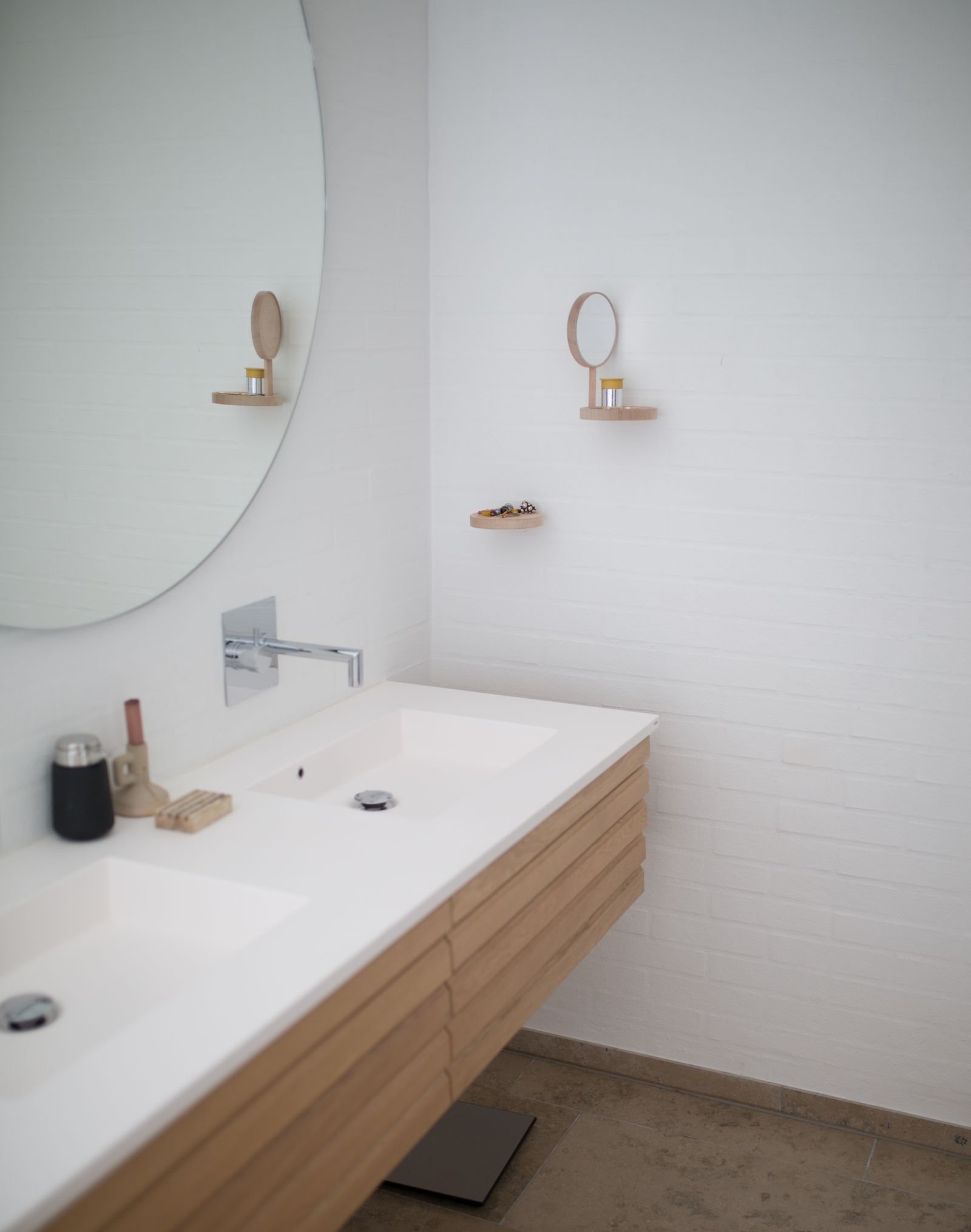 Small bathroom with a floating wood vanity, an oversized round mirror and small wall-mounted mirror sconces
