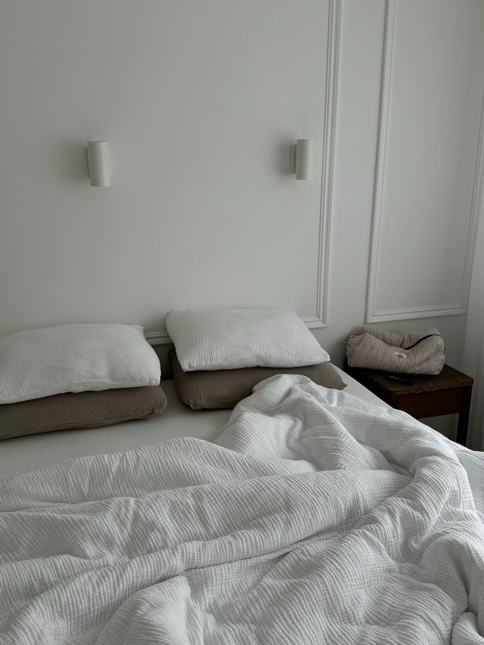 Small minimalist bedroom with wall-mounted sconces beside the bed instead of nightstand lamps