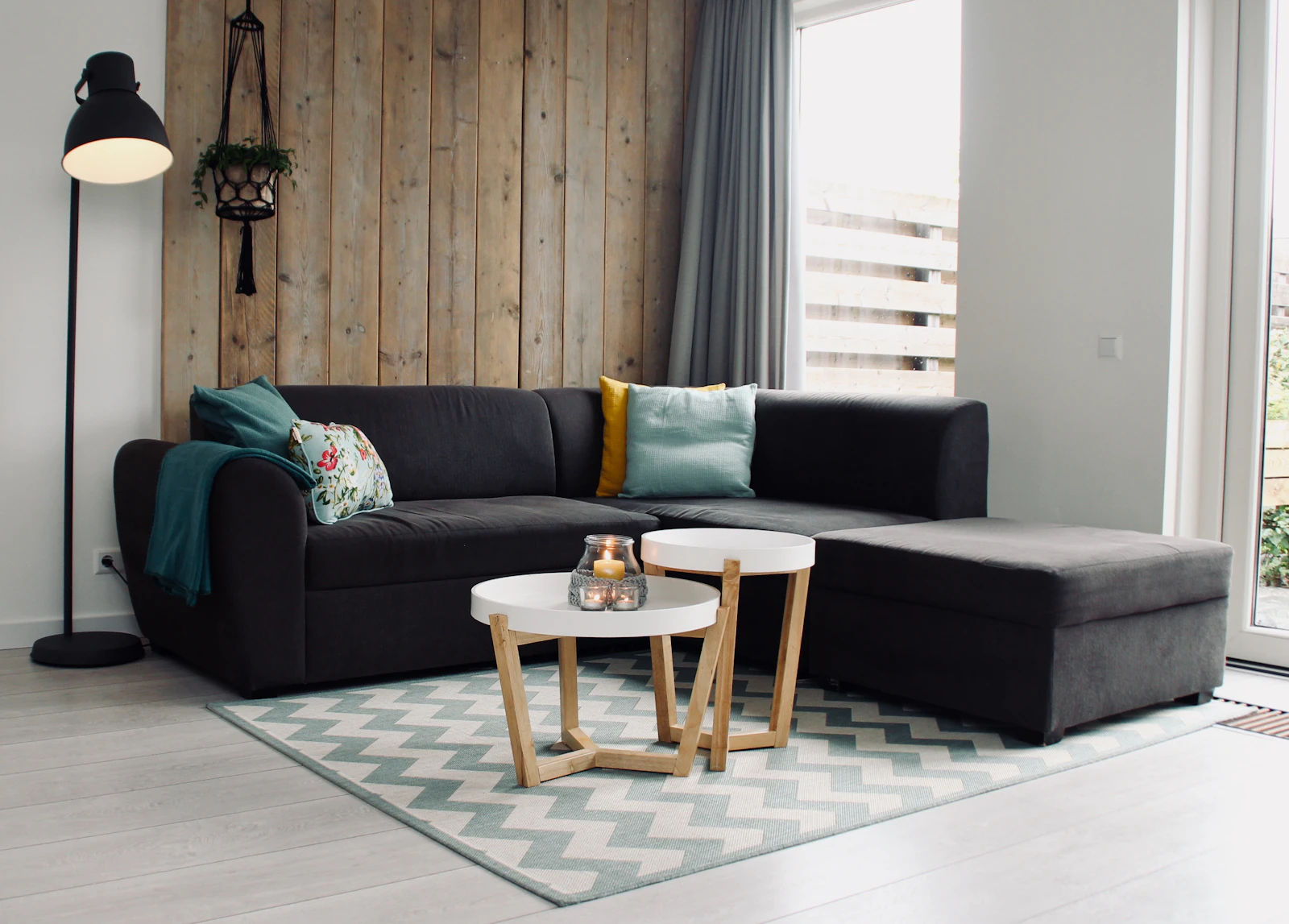 Compact living room with a slim sectional sofa, round coffee table and light-filled corner