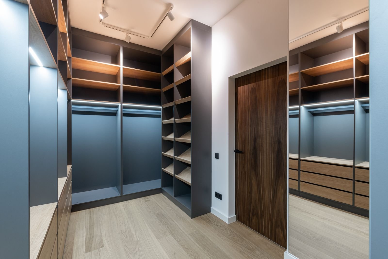 Organized walk-in closet with wood shelving, angled shoe cubbies and a hanging rod